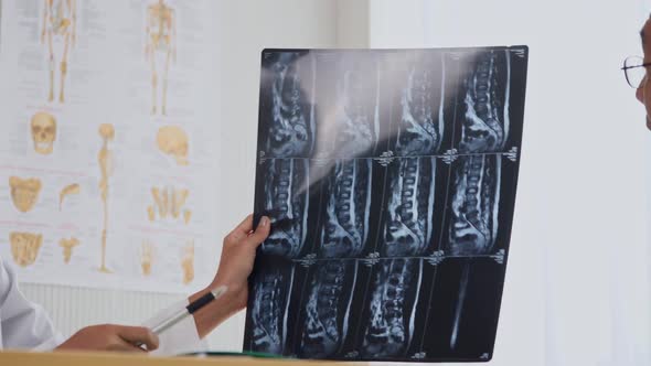 Expert doctor examining and explaining x-ray film to patient