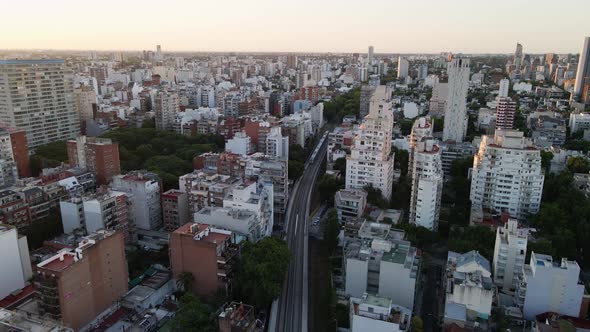 Dolly out flying over train rails surrounded by buildings in Belgrano neighborhood at sunset, Buenos