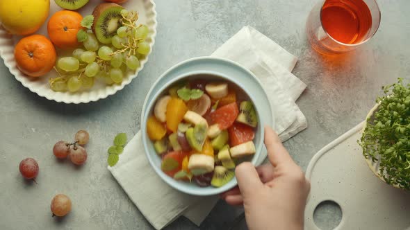 A man takes a bowl of fruit salad from the table