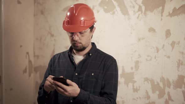 a Portrait of a Foreman Who Checks the Completed Work on the List on the Phone