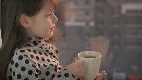 A child on the windowsill with a cup.