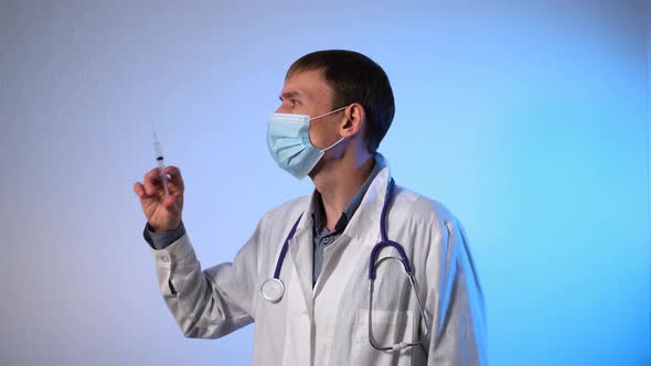 Masked Male Doctor with an Injection in Hands