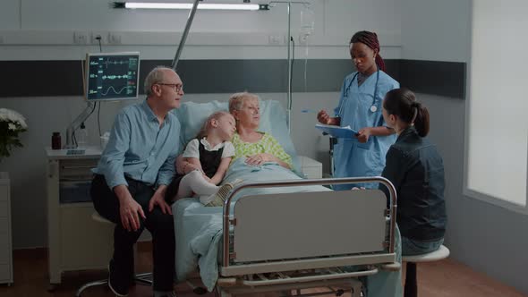 Nurse Doing Consultation with Sick Woman While Family Visits Her