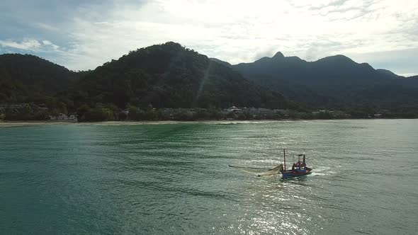 Aerial view of small fishing boat navigating on calm water, Ko Chang, Thailand.