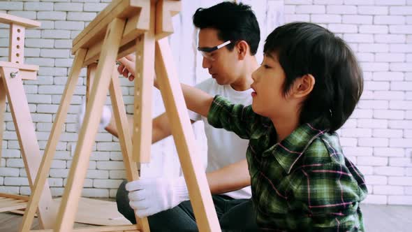 Carpenter Asian man teaching his son how to work with wood in workshop.