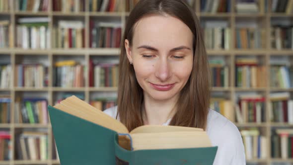 Young Woman Student Reading a Book in a Library