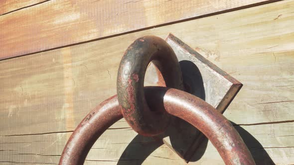 Ancient iron knocker on wooden surface 