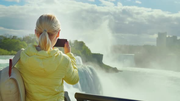 A Woman Tourist Takes Pictures of Niagara Falls in the USA