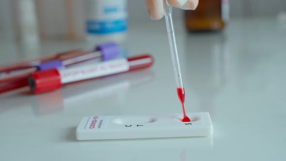 Doctor in Gloves Doing Rapid Test for Viral Disease Dripping Blood on Lab Card Kit Test