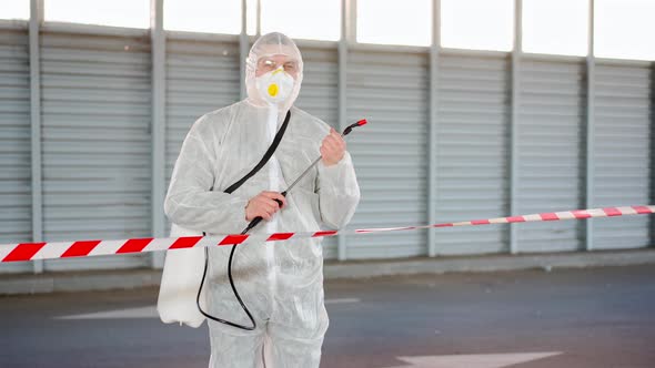 Man Worker Standing Border Line Warning Sign Disinfects Sprays Chemicals on Surface Against