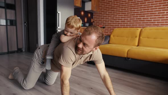 Father Playing with His Son Riding Him on the Back at Living Room