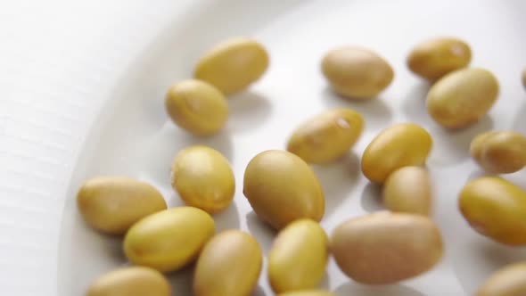 Uncooked peruvian bean on a white rotating dish. Falling Mayocoba grains. Macro. Canary legumes