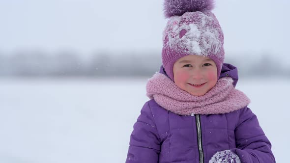 little girl in outerwear hat and scarf looking at camera