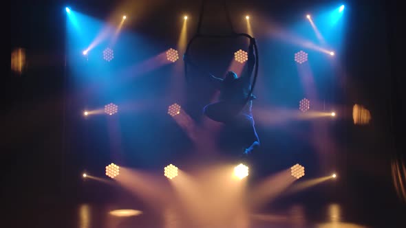 Silhouette Young Aerial Artist Woman Rotates Rapidly in an Aerial Circle. Filmed in a Dark Studio