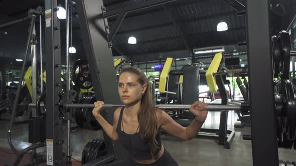 Portrait of strong caucasian woman using fitness equipment, bar, doing exercise, working out