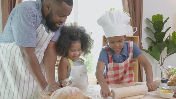 African American family with son and daughter rolling for thresh flour for cooking with father.