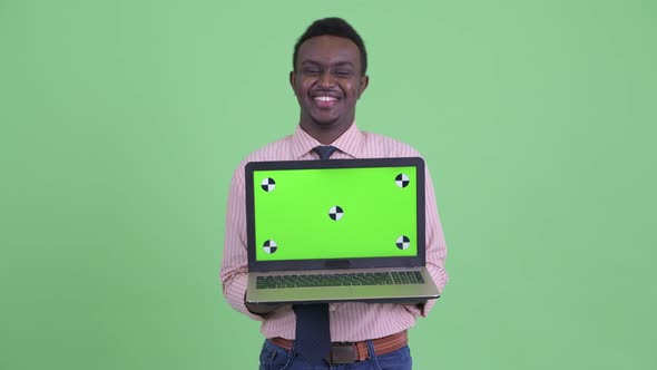 Happy Young African Businessman Talking While Showing Laptop