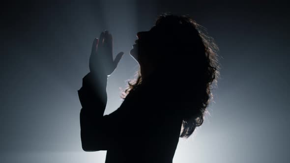 Silhouette Woman Praying in Darkness