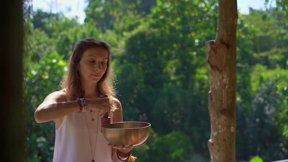 Superslowmotion Shot of a Woman Master of Asian Sacred Medicine Performs Tibetan Bowls Healing