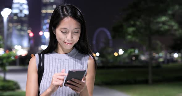 Woman using smart phone in city at night 