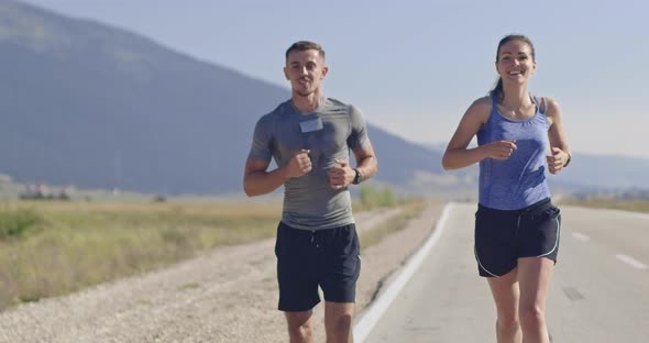 Tracking Slow Motion Shot of Sportive Couple Jogging Outdoors in the Morning Trail Running