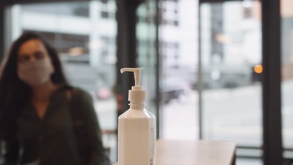 Female Office Worker Uses Hand Sanitiser In Reception As She Arrives For Work During Health Pandemic