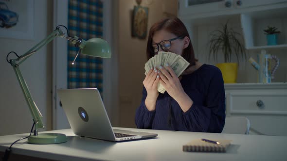 30s working from home woman counting dollars money cash and smelling money