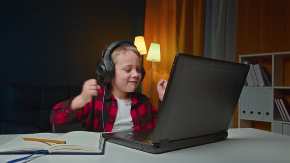 A Child with Headphones in Front of His Laptop Dancing alt