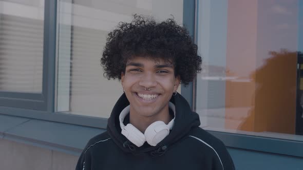 Caucasian Happy Beautiful African American Male in Black Hoodie with Headphones Standing Outdoors