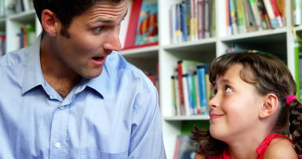 Teacher and school interacting with each other in library at school