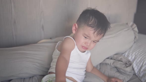 Slow motion shot of a cute two years old Asian boy who just wake up upset and crying  and ask his da