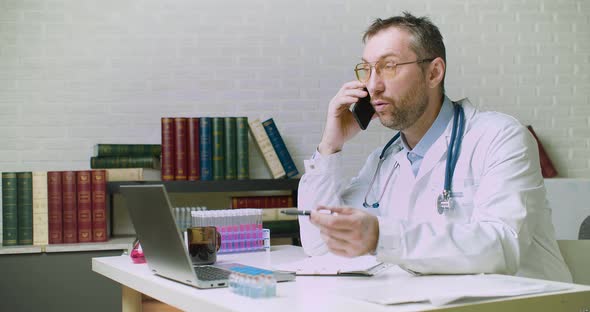 A Middleaged Doctor is Talking to a Patient on the Phone