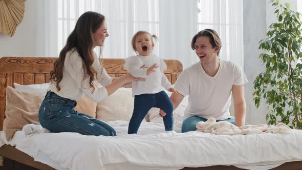 Happy Family Young Parents with Baby Small Daughter Have Fun Playing Jumping on Bed Cozy Bedroom