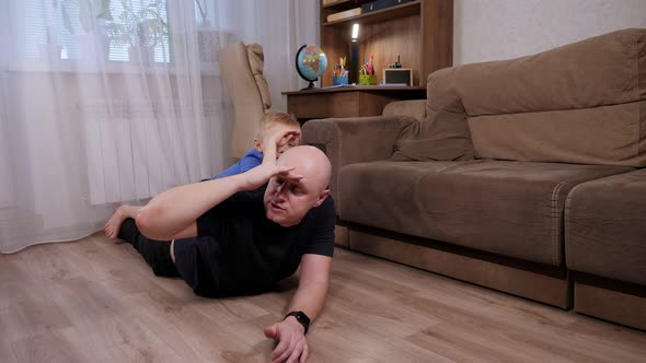 Father and Son Play Together at Home Lying on the Floor in the Living Room