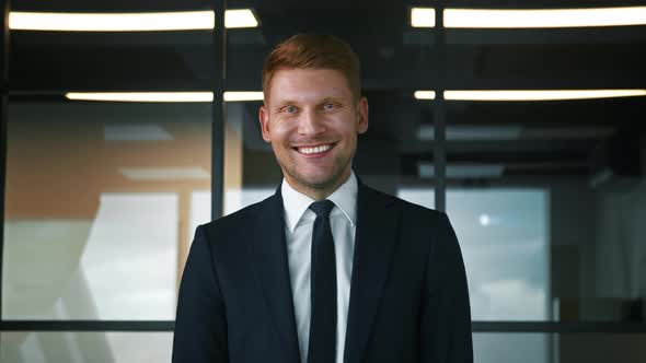 Smiling man in a suit in the office. Businessman looking at camera