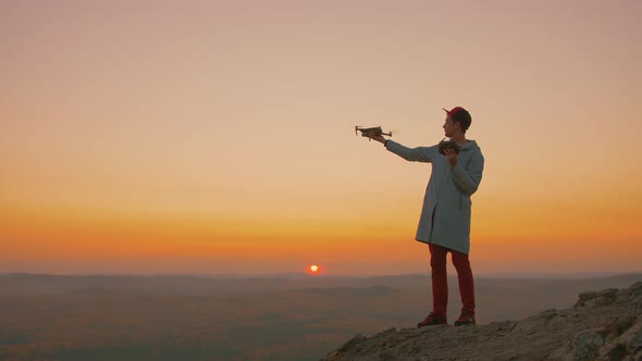 Man Standing on Top of Mountain Starts Drone From His Hand Aircraft Takes Off