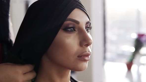 Beautiful Girl with Traditional Arabic Black Hijab Covering Her Head By Unrecognizable Woman Behind