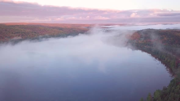 Aerial Sunrise Wide Shot Flying Through Cloud Fog To Reveal Misty Lakes And Pink Clouds And Fall For