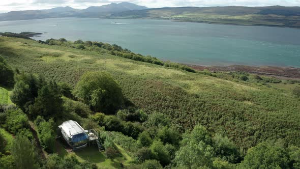 AERIAL - flying over an aluminium pod home on Scotlands West coast