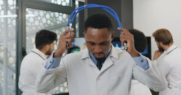 Doctor in White Coat which Putting on Stetoscope on His Neck and Looking Into Camera