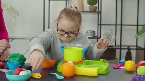 Lovely Down Syndrome Girl Learning to Cook with Kitchen Toy Set