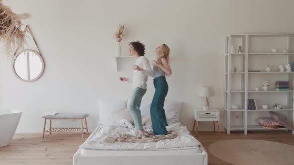 Happy Funky Young Romantic Couple Dancing Jumping in Bedroom