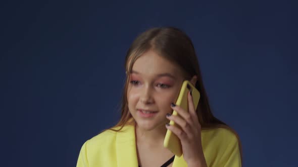 A Teenage Girl in Smart Clothes is Chatting on the Phone with Her Girlfriend