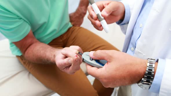 Mid-section of doctor examining senior patient blood sugar