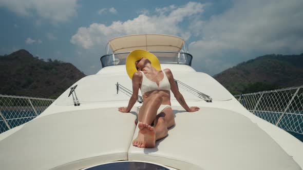 Beautiful Woman Wearing Straw Hat and White Bikini on a Yacht Enjoys the Journey