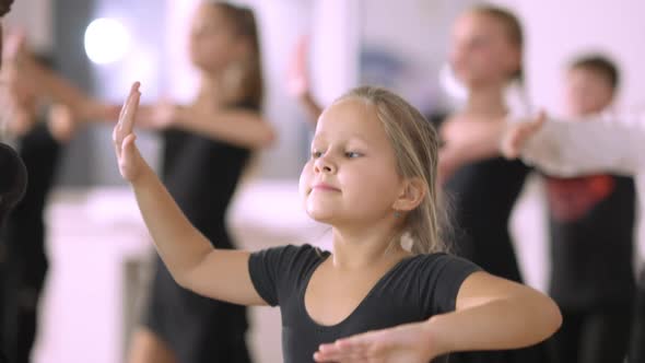 Pretty Serious Little Girl Taking Steps in Fourth Ballet Position in Dance Studio