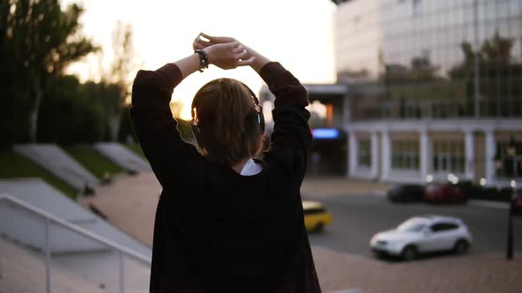 Footage of a Stylish Girl Dancing Outdoors on the Street with Modern Building on the Background