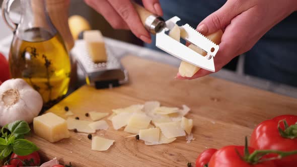 Slicing Italian Parmesan Cheese Over Wooden Cutting Board at Domestic Kitchen