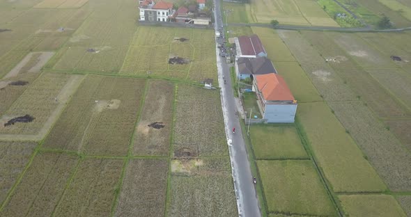 Aerial drone view of a man riding his motocross motorcycle on a road in Bali.