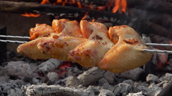 Closeup of Appetizing Chicken Wings on the Skewers Frying Above the Open Fire